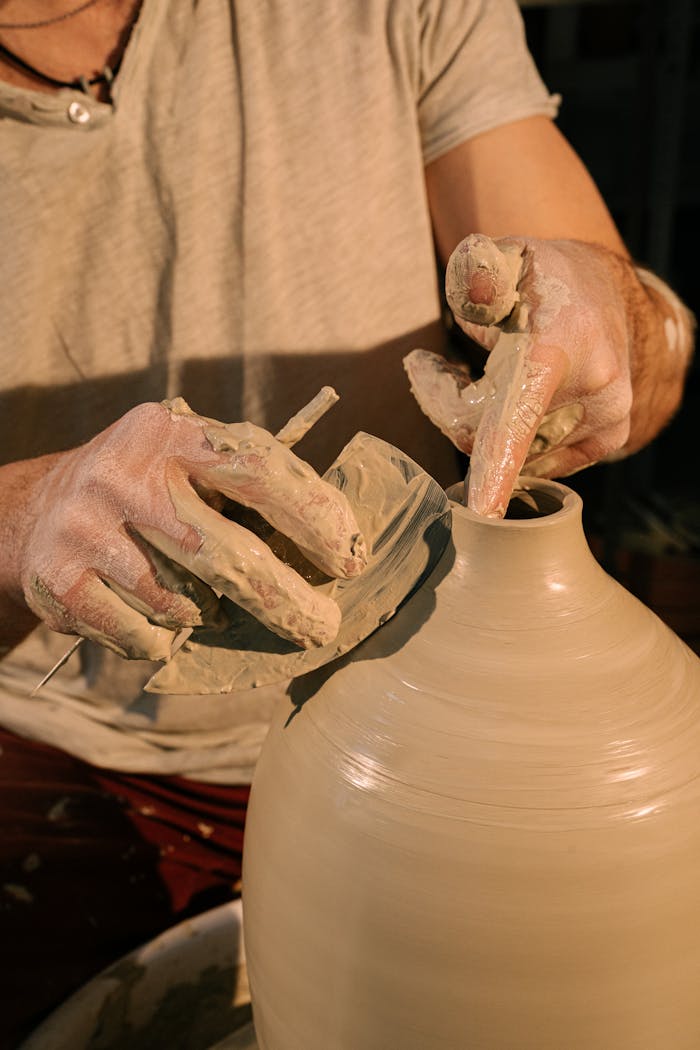 A detailed view of a person molding a clay pot in a pottery workshop, highlighting craftsmanship.