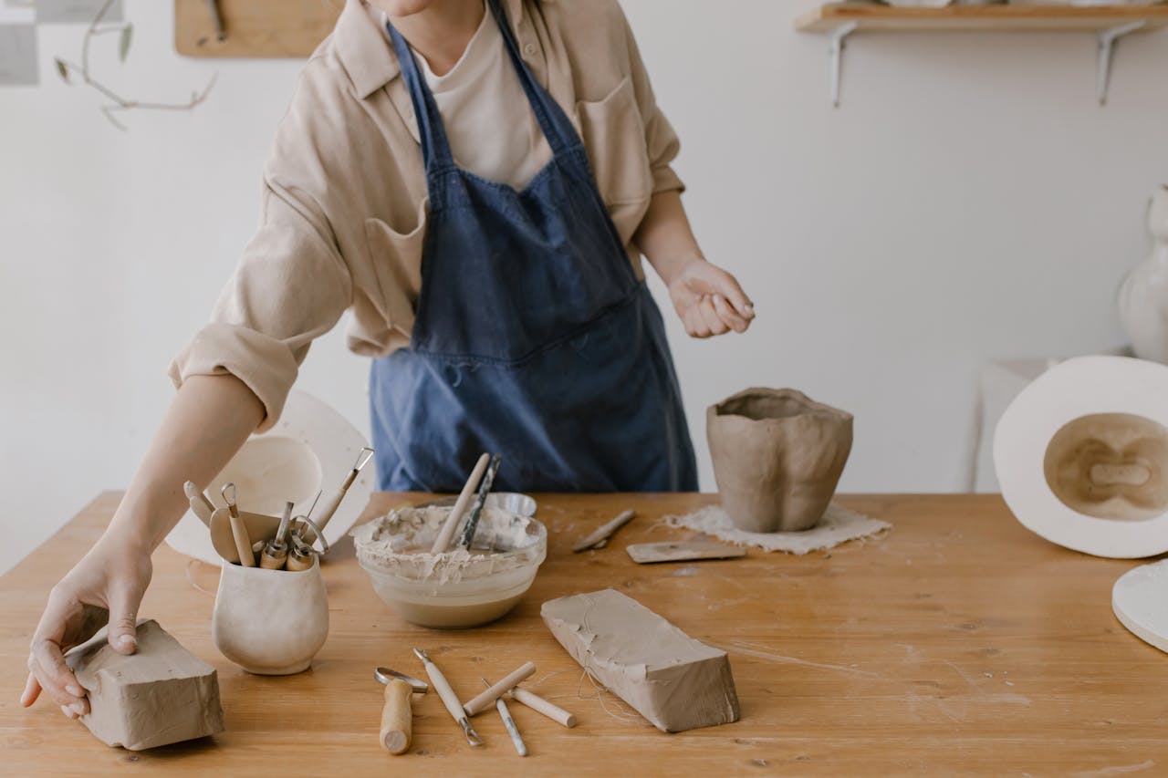 A woman working on pottery in a workshop, showcasing artisan tools and clay.
