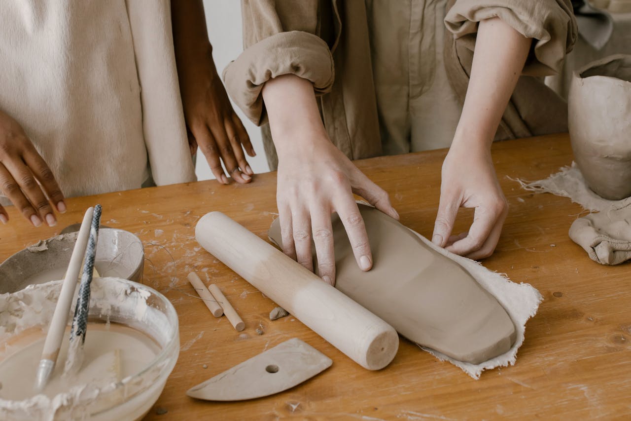 Hands shaping clay at a pottery workshop, emphasizing artisanal craftsmanship.